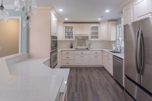 A kitchen with white cabinets, a stainless steel refrigerator, and a wooden countertop. - Downtown Conway 3 bedroom home in picturesque neighborhood (Conway)