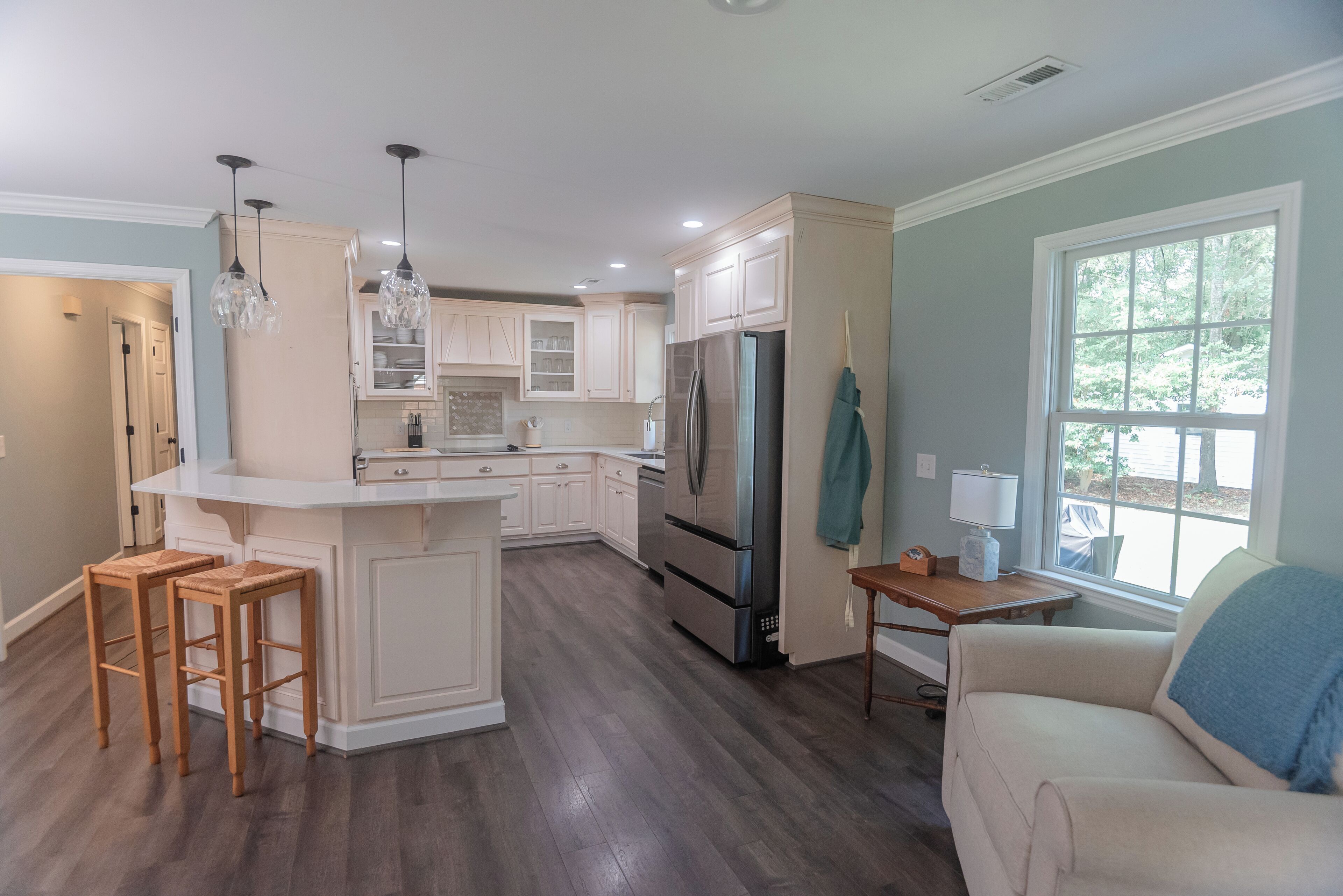 A modern kitchen with a central island, stainless steel appliances, and wooden bar stools.