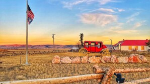 Paisaje rural con un asta de banderín, un carrete rojo y un edificio con tejado rojo.