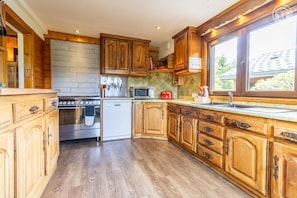 A kitchen with wooden cabinets, a stainless steel stove, a dishwasher, and a microwave. - The Chalet Des Sangliers (SEEZ)