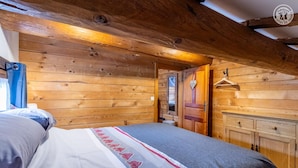 Een houten kamer met een bed, een kledingkast en een deur naar een andere kamer.