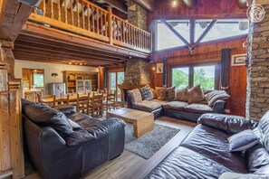 A rustic cabin interior with a dining area, a fireplace, and a balcony. - The Chalet Des Sangliers (SEEZ)