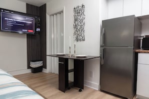 Une cuisine moderne dotée d’un réfrigérateur encastré, d’un téléviseur à écran plat fixé au mur et d’un élément décoratif mural.