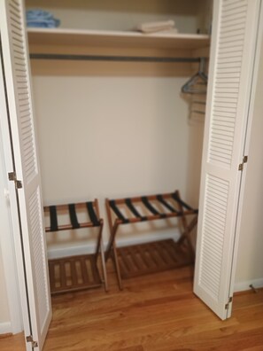 Ein Schrank mit hölzernen Bänken, einem Regal mit gefalteter Kleidung und einer Tür mit Lamellen.
