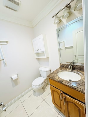 Un bagno con WC, lavabo, mobile lavabo, specchio e portasciugamani.