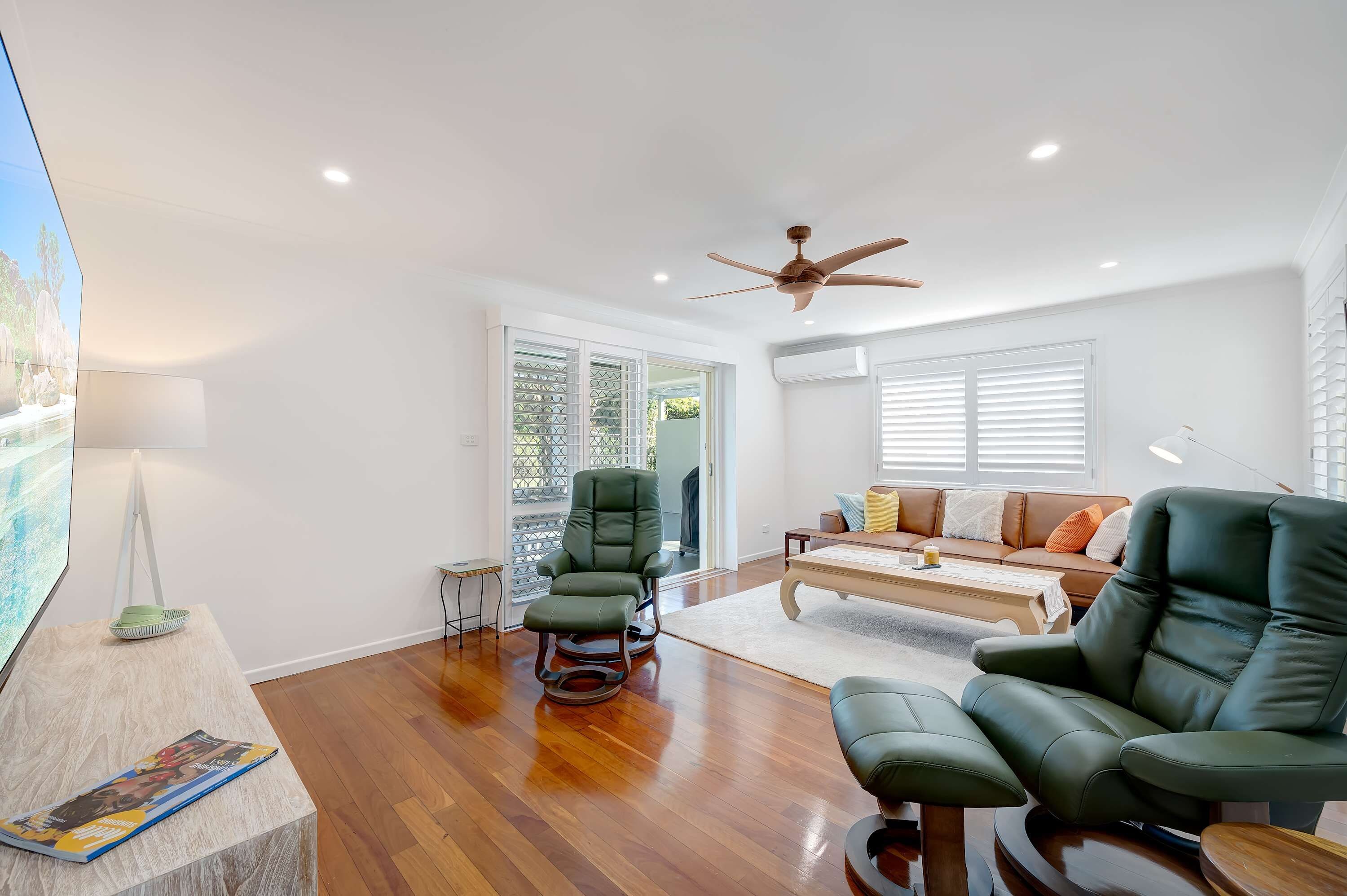 A spacious living room with a ceiling fan, a sofa, a recliner, and a coffee table.