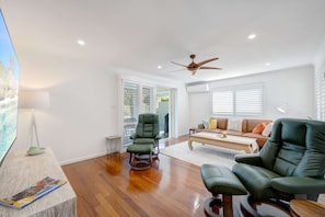 A spacious living room with a ceiling fan, a sofa, a recliner, and a coffee table. - Alice by the Lake Currimundi (Currimundi)