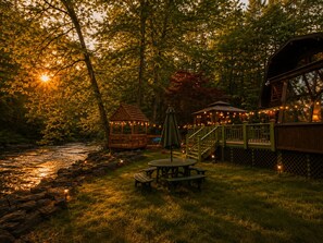 A riverside outdoor area with a gazebo, picnic table, and deck with string lights. - Grand River Cabin I Fire Pit I Deck I Pool Table (East Stroudsburg)