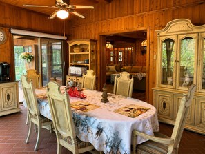 A wooden cabin interior with a dining table, chairs, a ceiling fan, and a view of the outdoors. - Grand River Cabin I Fire Pit I Deck I Pool Table (East Stroudsburg)