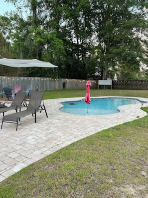 Un jardin avec une piscine, des chaises longues et une clôture en bois.