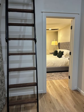 Une chambre à coucher avec un lit, une table de chevet, une lampe et un plancher en bois.