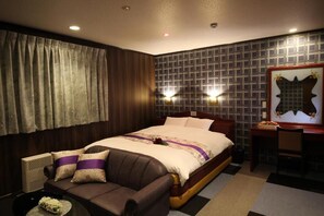 A hotel room with a large bed, a sofa, a desk, and a wall-mounted TV. - hotel dolphia (daisen)