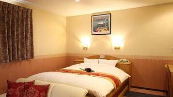 A hotel room with a bed, a nightstand, a chair, a painting on the wall, and two wall-mounted lights.