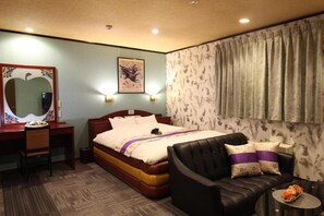 A hotel room with a bed, a desk, a chair, a sofa, and a small table with flowers. - hotel dolphia (daisen)