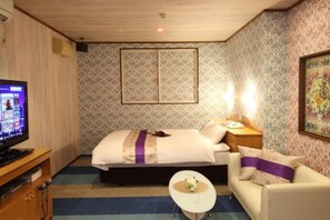 A hotel room with a bed, a television, a small table, a sofa, and patterned wallpaper. - hotel dolphia (daisen)