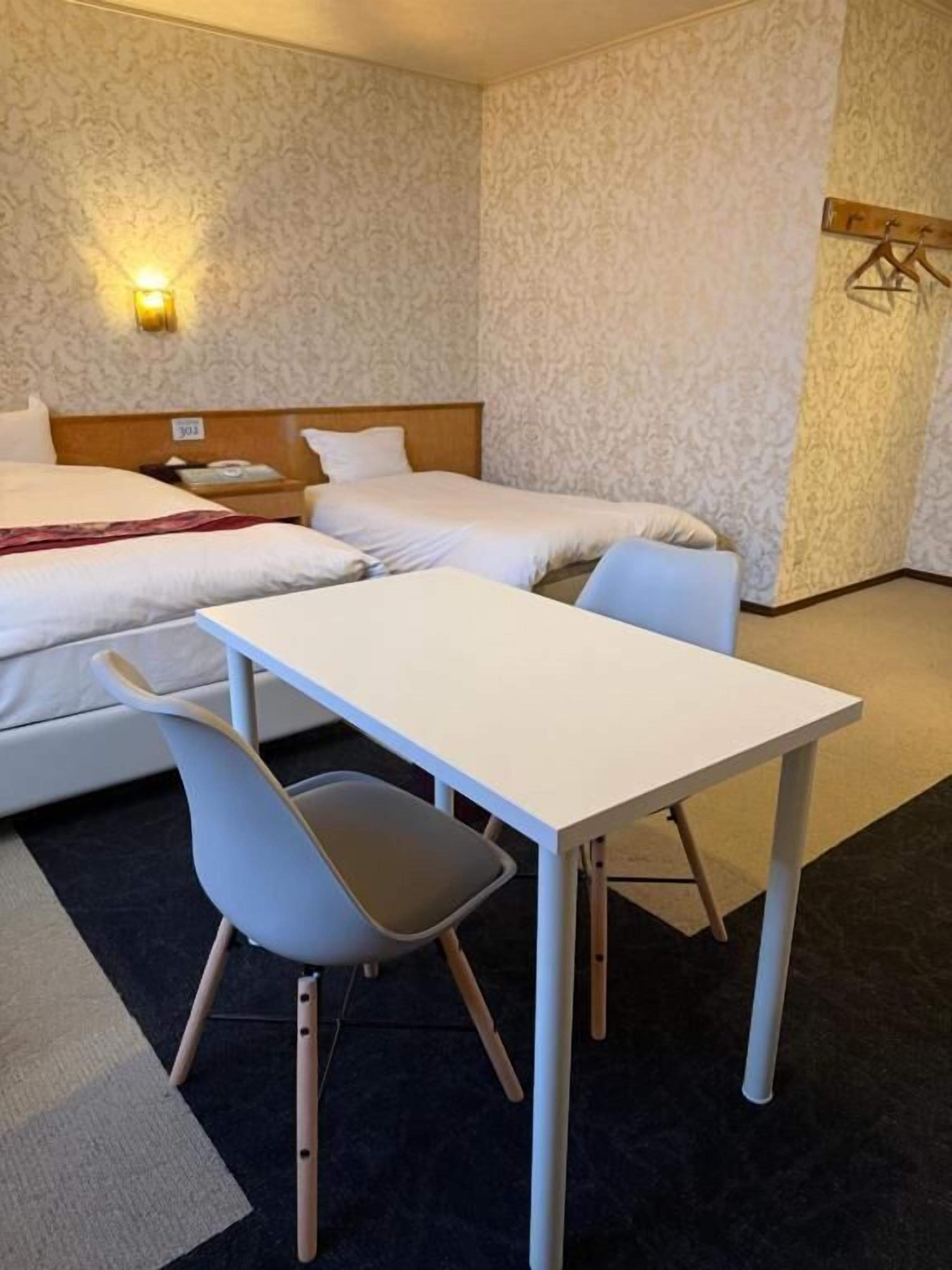 Una habitación de hotel con dos camas, una mesa y una silla.