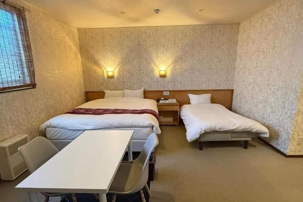 Habitación de hotel con dos camas, un escritorio y dos lámparas fijadas a la pared.