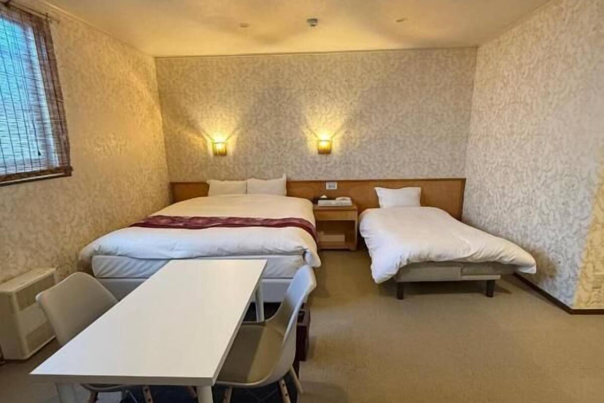 Ein Hotelzimmer mit zwei Betten, einem Schreibtisch und zwei Wandleuchten.