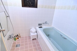 A bathroom with a bathtub, toilet, shower, and a small step stool.