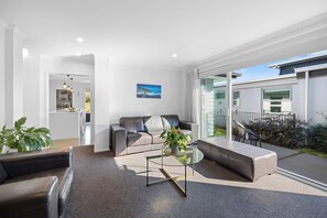 Ein modernes Wohnzimmer mit einer Couch, einem Glastisch und Blick ins Freie.