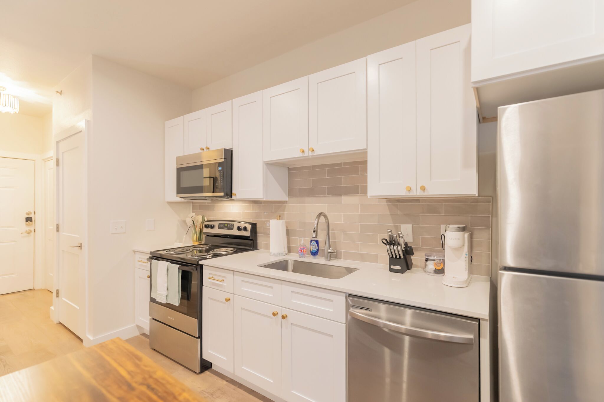 A modern kitchen with white cabinets, stainless steel appliances, and a tiled backsplash.