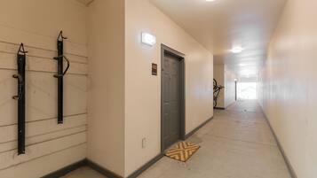 A hallway with a door marked '402,' a light fixture above it, and a doormat on the floor.