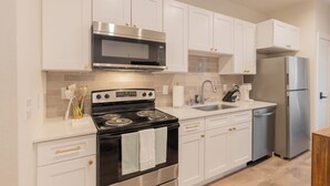 A modern kitchen with white cabinets, stainless steel appliances, and a tiled backsplash.