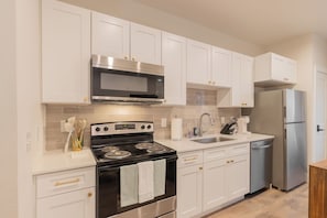 Una cocina moderna con armarios blancos, electrodomésticos de acero inoxidable y salpicadero de azulejos.