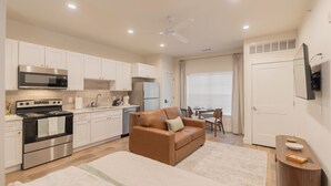 A compact kitchen with modern appliances, a sofa, and a dining area with a table and chairs.