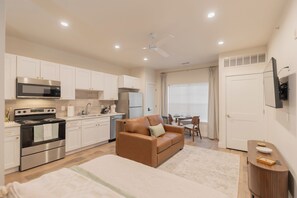 Una cocina compacta con electrodomésticos modernos, un sofá y un comedor con mesa y sillas.