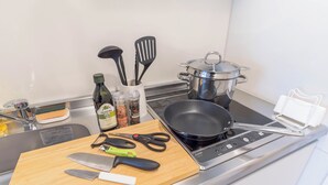 Eine Küche mit Herd, Töpfen, Schneidebrett und Geschirr sowie einem Spülbecken.