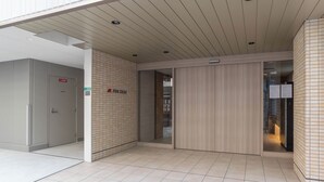 Ein moderner Hotelzugang mit Fliesenboden, einer Holzwand und einer Glastür zum Innenbereich.