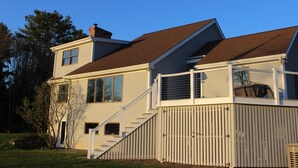 A two-story house with a deck, a chimney, and a staircase leading to the upper floor. - Serene 4-bedroom house with water access in charming Phippsburg (Phippsburg)
