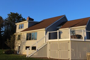 A two-story house with a deck, a chimney, and a staircase leading to the upper floor. - Serene 4-bedroom house with water access in charming Phippsburg (Phippsburg)