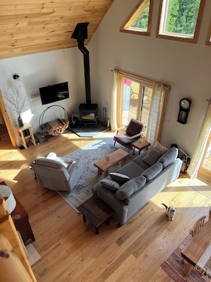Un salon spacieux avec un plafond en bois, une cheminée, un canapé, une table basse et un téléviseur.