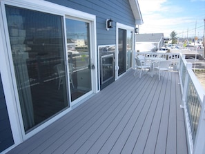 Um terraço com portas de correr, mobiliário de exterior branco e vista para uma marina.