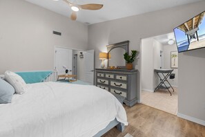 A bedroom with a bed, dresser, mirror, lamp, and a TV. - Waterfront Oasis - Heated Pool, Kayaks + Game Room (Palm Coast)