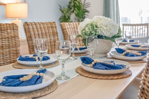 A dining table set with plates, glasses, and blue napkins. - Waterfront Oasis - Heated Pool, Kayaks + Game Room (Palm Coast)