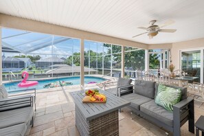 En overdækket terrasse med pool, udendørs møbler og udsigt over det omkringliggende landskab.