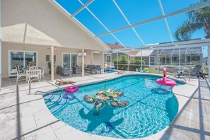 An indoor swimming pool with a glass ceiling, lounge chairs, and a small garden area. - Waterfront Oasis - Heated Pool, Kayaks + Game Room (Palm Coast)