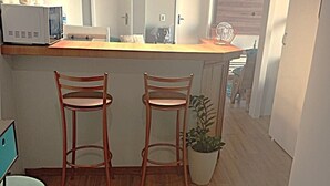 Une cuisine avec des tabourets en bois, une plante en pot et un plan de travail avec des appareils électroménagers.