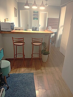 A kitchen with wooden stools, a potted plant, and a countertop with appliances. - Beachfront property with two oceanfront balconies (São Vicente)