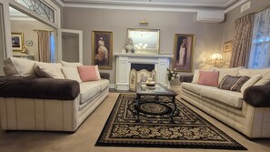A traditional living room with two sofas, a fireplace, and a decorative mirror.
