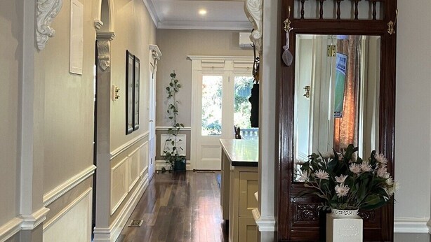 A hallway with a wooden cabinet and a mirror, a door with a window, and a plant. - Crofton House @ Port of Echuca - Heritage (Echuca)