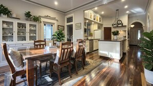 A spacious kitchen with wooden cabinets, a dining area with a large table and chairs, and a central island. - Crofton House @ Port of Echuca - Heritage (Echuca)