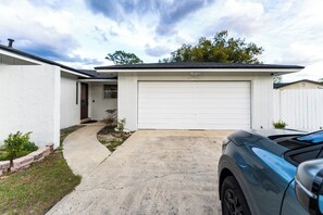 A residential garage with a concrete driveway, a parked car, and a white exterior wall.