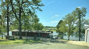 Un chalet rustique avec un quai, entourĂ© dâarbres et bordant un lac.
