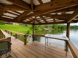 Eine Holzterrasse mit Seeblick, ein überdachter Sitzbereich und ein Steg, der ins Wasser führt.