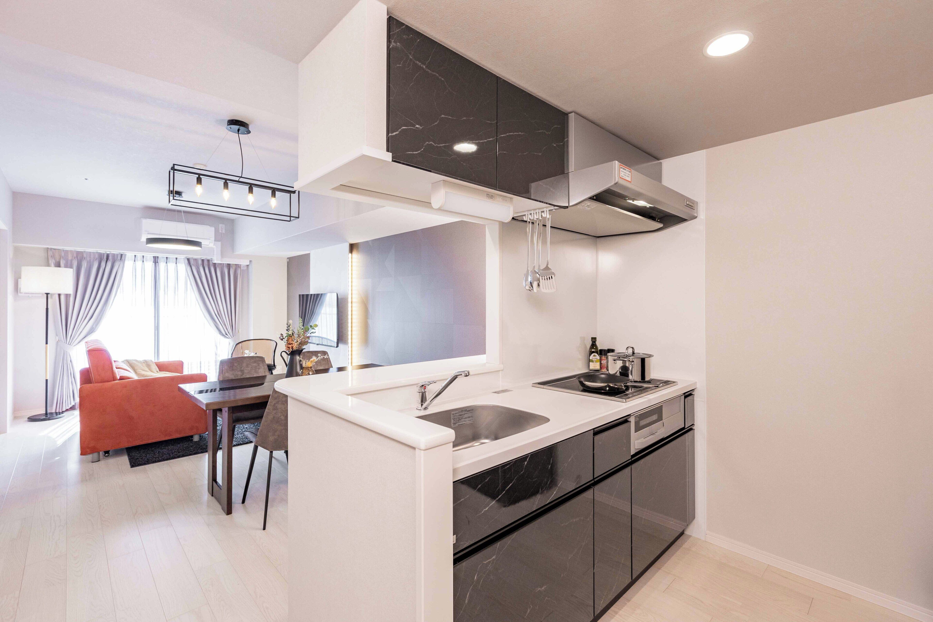 A modern kitchen with a built-in stove, sink, and black cabinets.