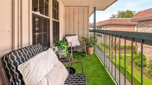 A balcony with a sofa, two chairs, and potted plants. - World Cup Ready 2BR Near NRG Stadium Skip the Parking (Houston)